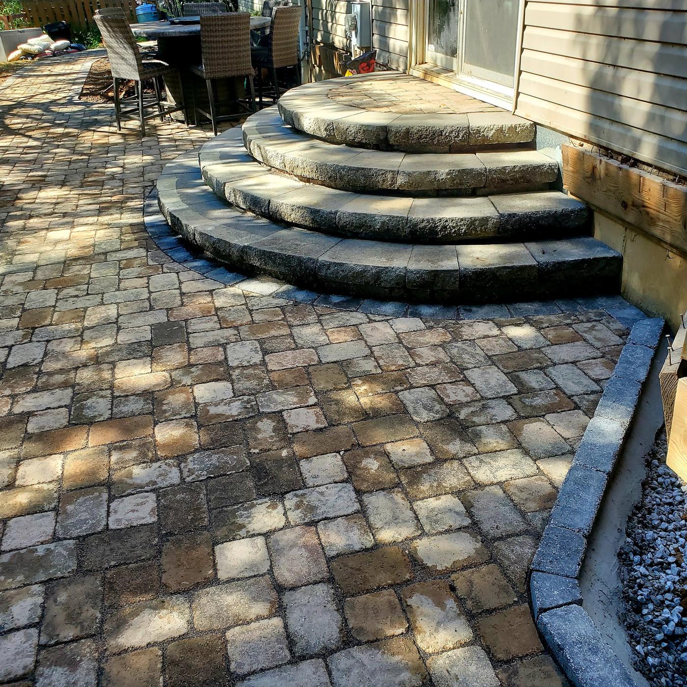 Three curved paver steps with bullnose treads leading down to a tumbled-paver patio