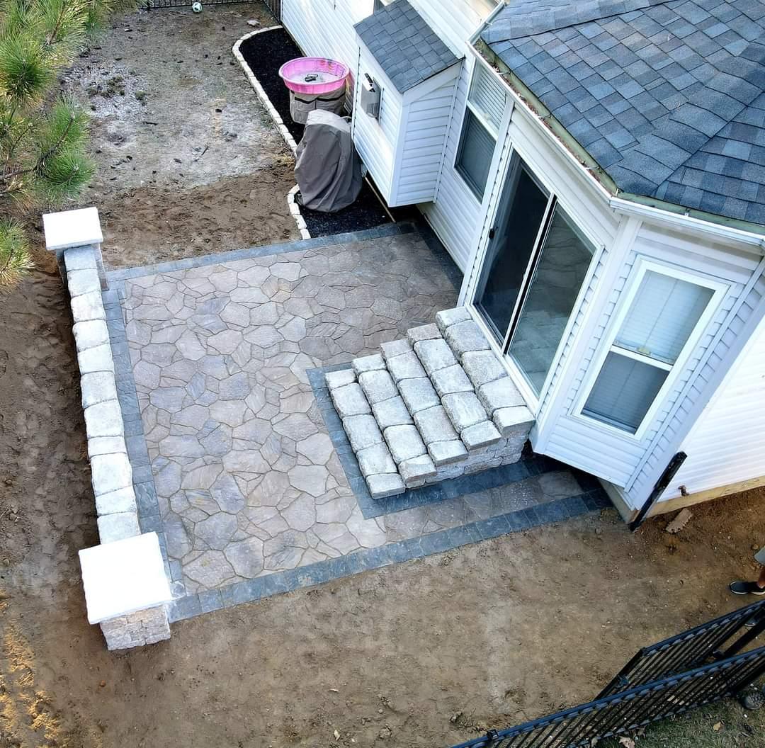 Top-down view of a flagstone-pattern paver patio with block pillars and steps